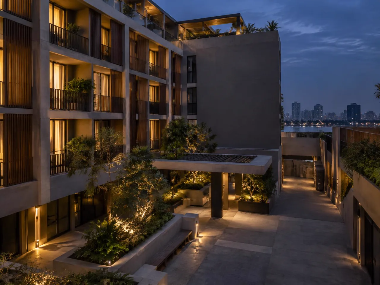 Contemporary mixed-use property with illuminated residences, landscaped courtyard and service access at dusk